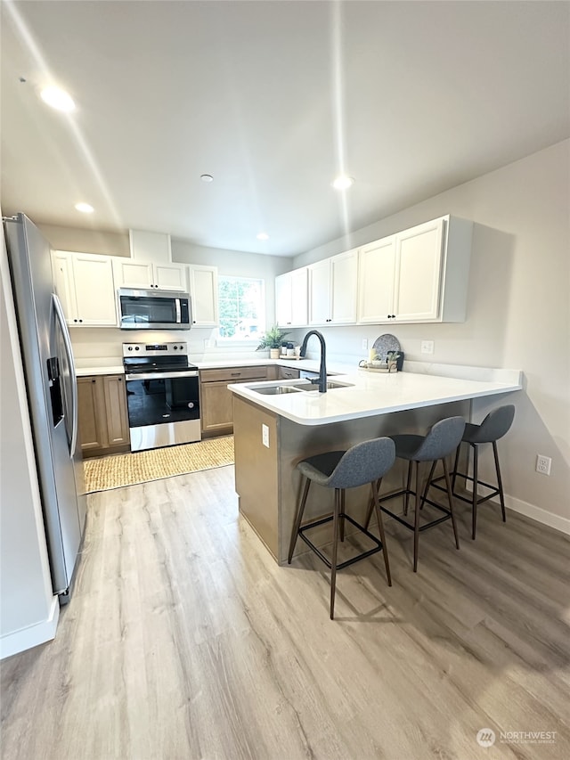 kitchen with stainless steel appliances, kitchen peninsula, sink, and white cabinets