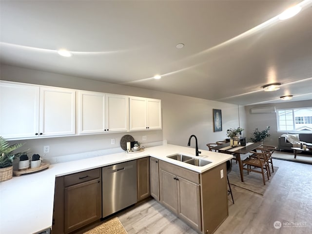 kitchen with sink, white cabinets, stainless steel dishwasher, kitchen peninsula, and light wood-type flooring