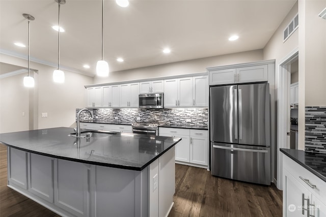 kitchen with stainless steel appliances, sink, pendant lighting, white cabinetry, and an island with sink