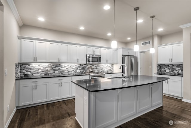 kitchen featuring appliances with stainless steel finishes, sink, white cabinetry, hanging light fixtures, and an island with sink