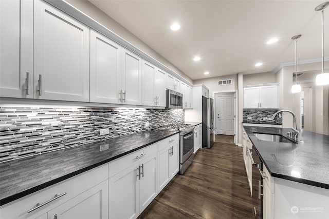 kitchen featuring white cabinetry, sink, stainless steel appliances, backsplash, and decorative light fixtures