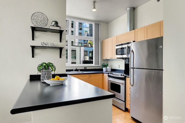 kitchen with sink, kitchen peninsula, stainless steel appliances, and light brown cabinetry