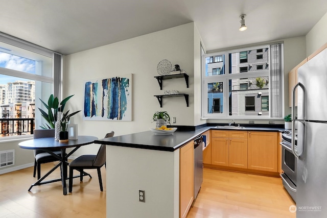 kitchen featuring light brown cabinetry, stainless steel appliances, light hardwood / wood-style flooring, and sink