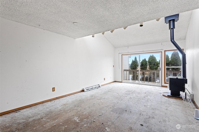 unfurnished living room featuring a wood stove, a textured ceiling, and vaulted ceiling