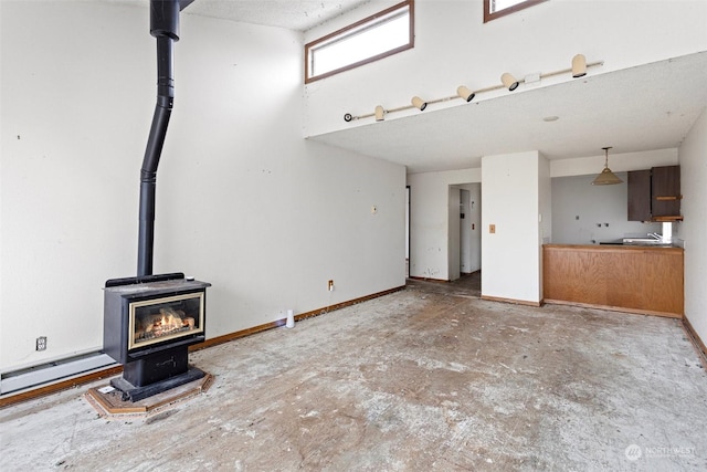 unfurnished living room with a textured ceiling, concrete floors, and a wood stove