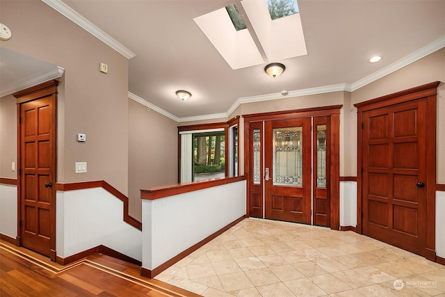 entryway with light wood-type flooring, a skylight, and ornamental molding