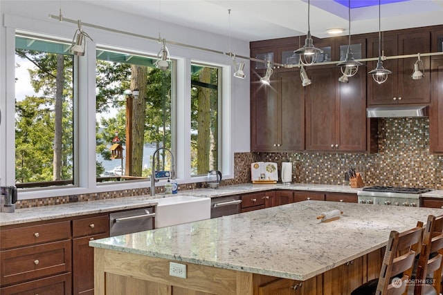 kitchen featuring a center island, pendant lighting, light stone counters, decorative backsplash, and extractor fan