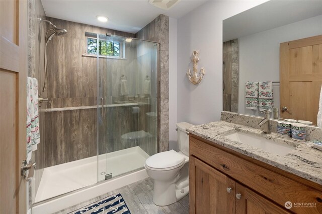 bathroom with toilet, walk in shower, vanity, and hardwood / wood-style flooring