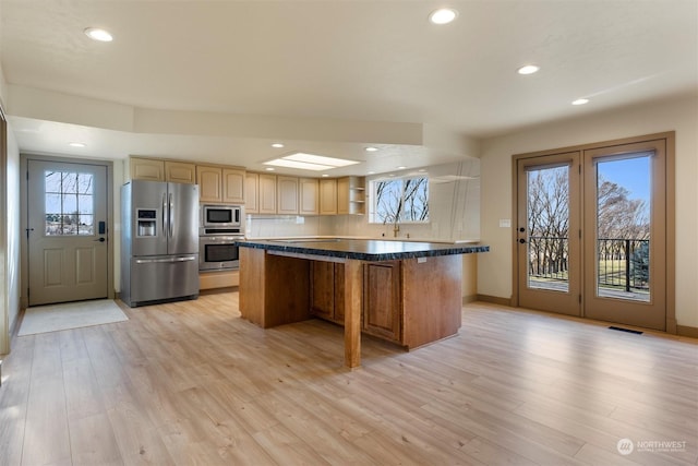 kitchen featuring light wood-type flooring, stainless steel appliances, sink, a kitchen island, and a breakfast bar area