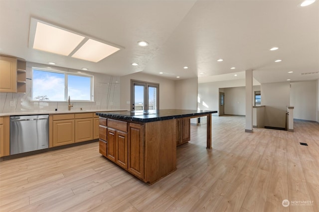 kitchen featuring dishwasher, a center island, sink, tasteful backsplash, and light hardwood / wood-style flooring