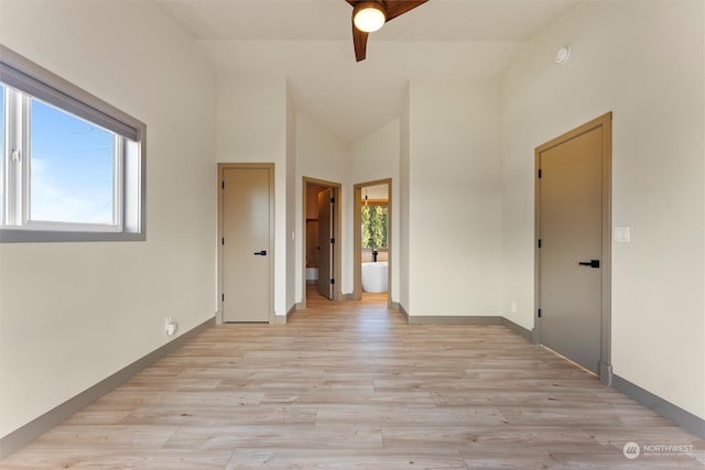 empty room with ceiling fan, high vaulted ceiling, a healthy amount of sunlight, and light wood-type flooring