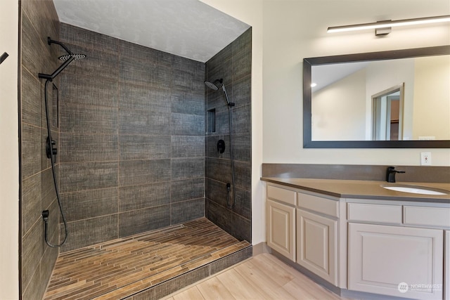 bathroom featuring a tile shower, vanity, and hardwood / wood-style flooring