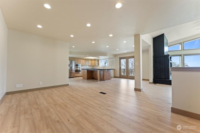 unfurnished living room with a fireplace, plenty of natural light, and light wood-type flooring