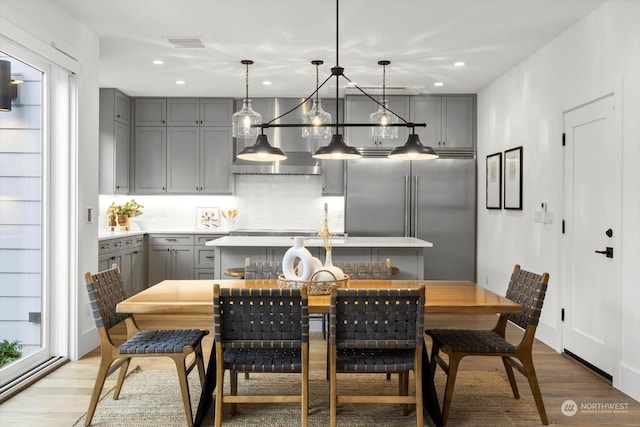 kitchen with gray cabinetry, high end refrigerator, hanging light fixtures, and light wood-type flooring