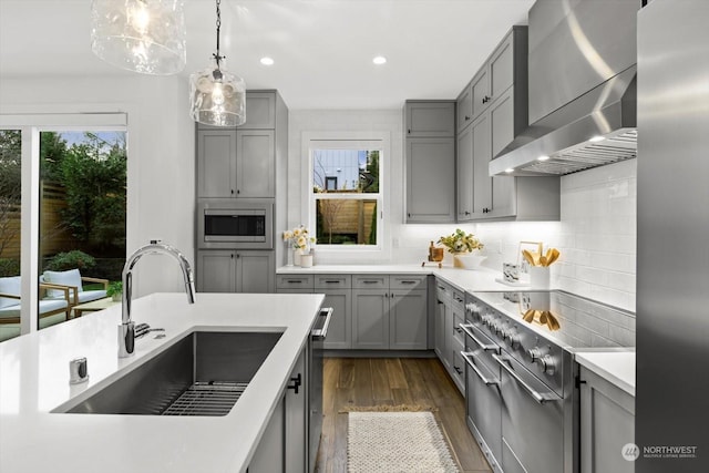 kitchen featuring decorative backsplash, plenty of natural light, wall chimney exhaust hood, and sink