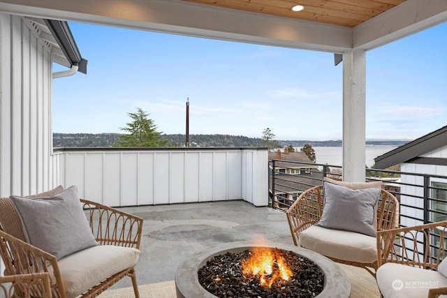 balcony with a water view and an outdoor fire pit