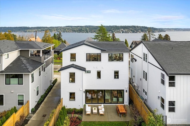 rear view of house with outdoor lounge area, a patio area, and a water view