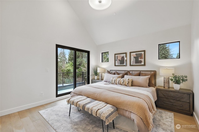 bedroom featuring access to exterior, light wood-type flooring, and high vaulted ceiling