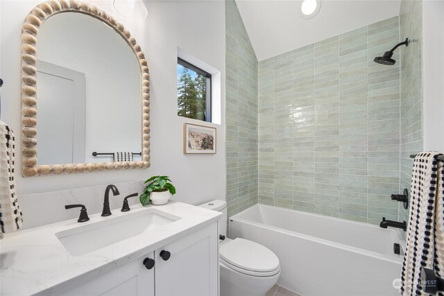 full bathroom featuring vanity, toilet, tiled shower / bath, and lofted ceiling