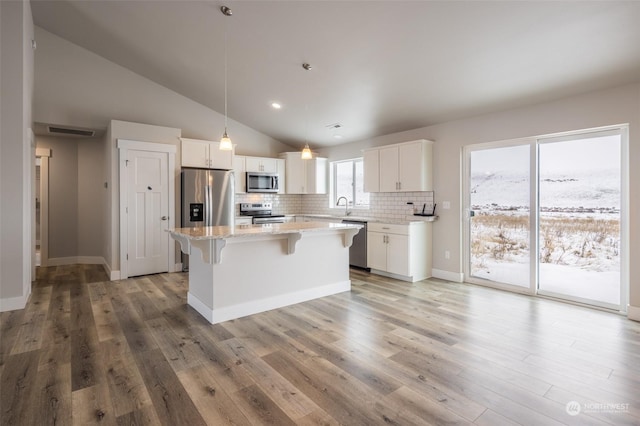 kitchen with appliances with stainless steel finishes, pendant lighting, sink, white cabinets, and a center island