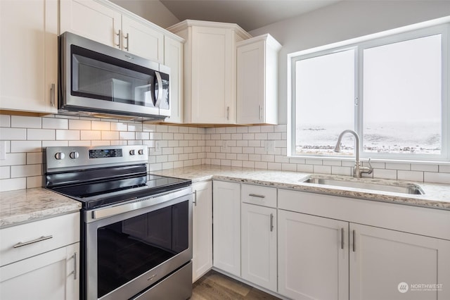 kitchen with white cabinetry, sink, backsplash, stainless steel appliances, and light stone countertops