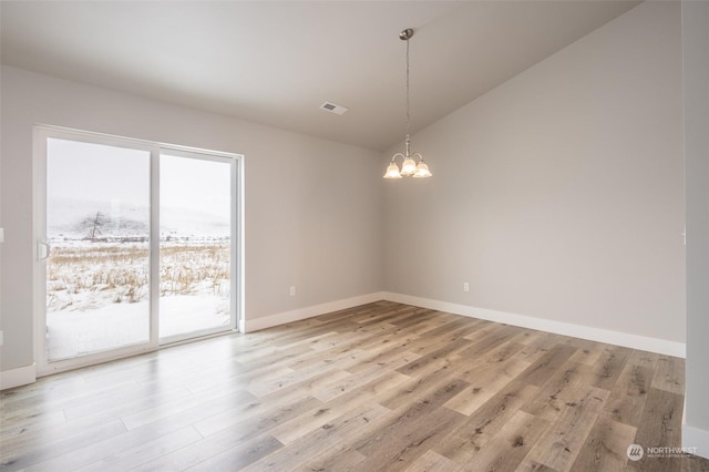 empty room with vaulted ceiling, a chandelier, and light wood-type flooring