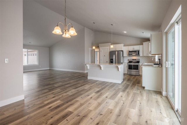 kitchen featuring white cabinetry, appliances with stainless steel finishes, a center island, and hanging light fixtures