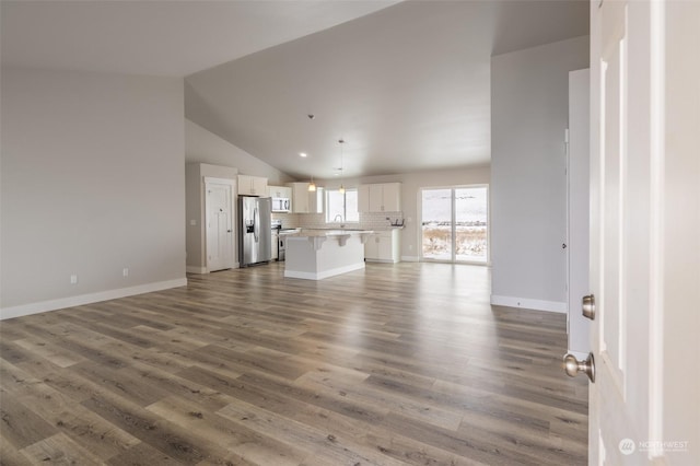 unfurnished living room with wood-type flooring, vaulted ceiling, and sink