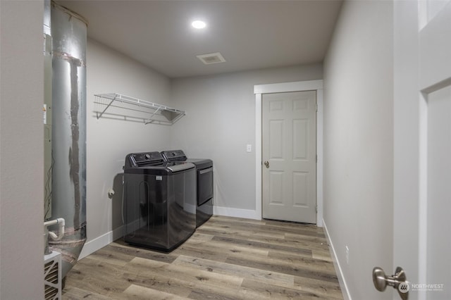 washroom with separate washer and dryer and light hardwood / wood-style flooring