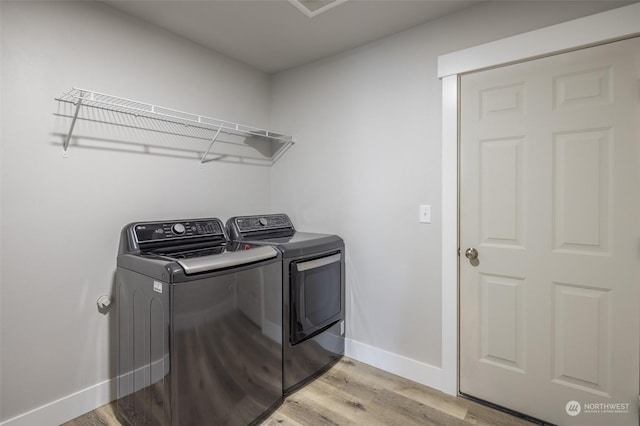 clothes washing area featuring washing machine and clothes dryer and light wood-type flooring