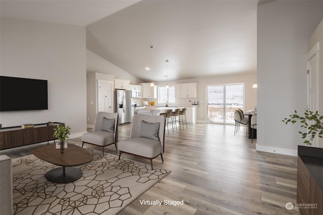 living room with high vaulted ceiling and light hardwood / wood-style flooring