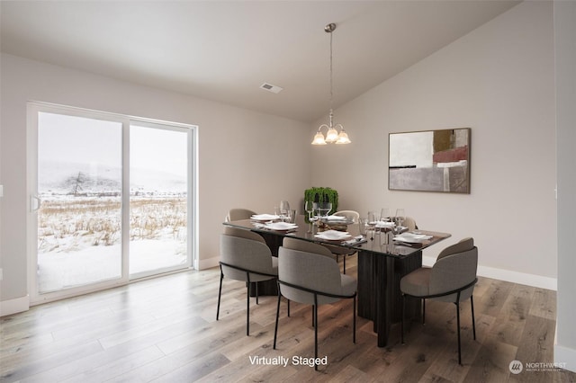 dining area featuring lofted ceiling, hardwood / wood-style flooring, and a chandelier