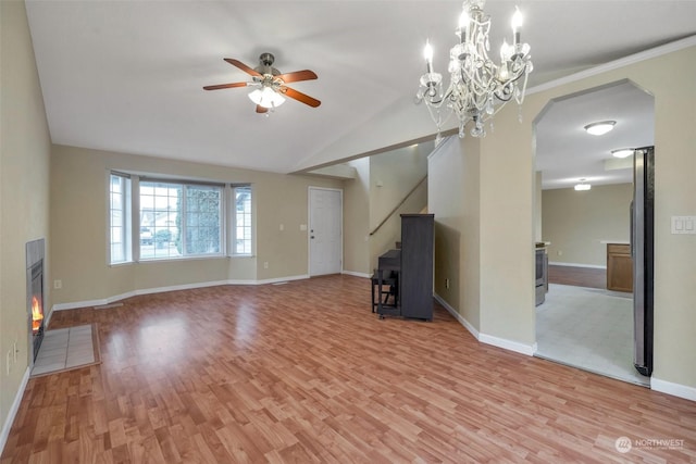 unfurnished living room with ceiling fan with notable chandelier, light wood-type flooring, and vaulted ceiling