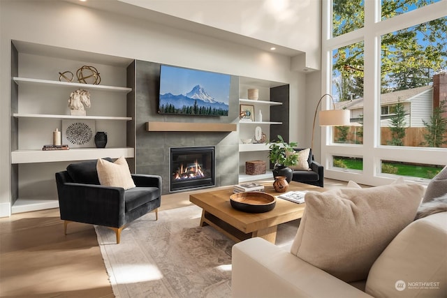 living room with a tile fireplace, a high ceiling, and built in features