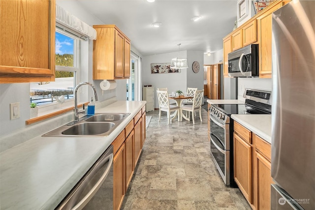 kitchen with sink, an inviting chandelier, lofted ceiling, hanging light fixtures, and appliances with stainless steel finishes