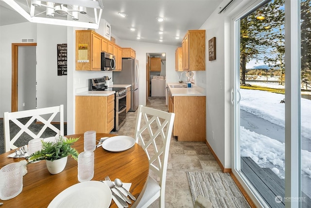 kitchen featuring sink, washer / clothes dryer, decorative light fixtures, tasteful backsplash, and appliances with stainless steel finishes