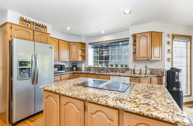 kitchen with a center island, sink, light wood-type flooring, appliances with stainless steel finishes, and light stone counters