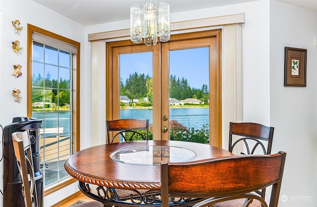 dining room featuring french doors, a water view, and an inviting chandelier