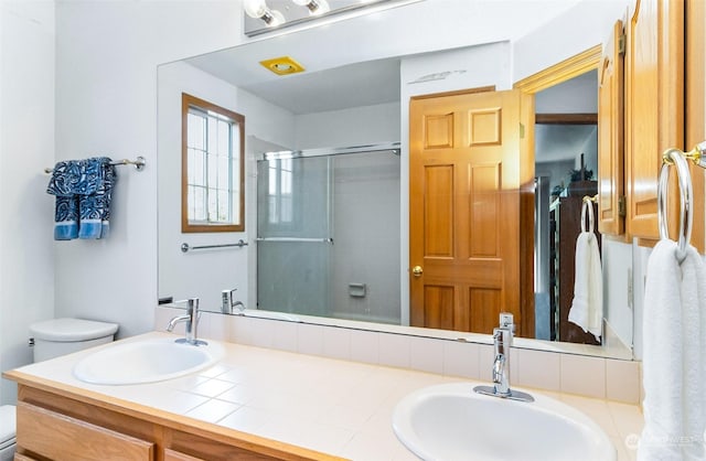 bathroom with vanity, toilet, and a shower with door