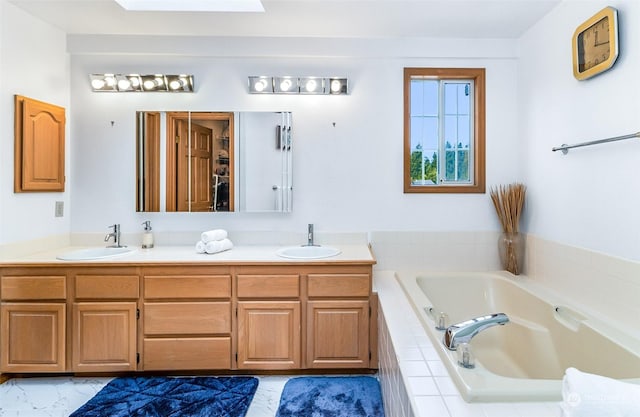 bathroom featuring tiled tub, vanity, and a skylight