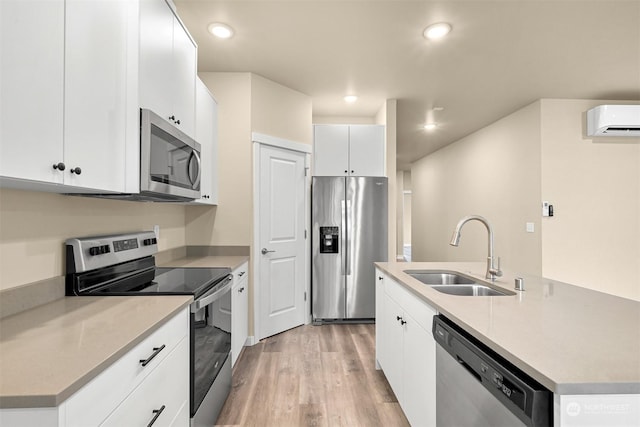 kitchen featuring a wall mounted air conditioner, stainless steel appliances, sink, white cabinetry, and an island with sink