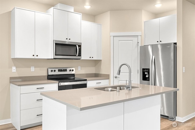 kitchen with white cabinets, stainless steel appliances, a kitchen island with sink, and sink