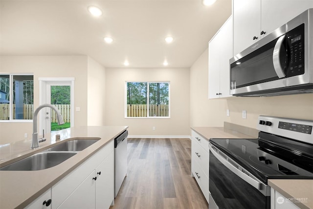 kitchen featuring white cabinetry, sink, light wood-type flooring, and appliances with stainless steel finishes