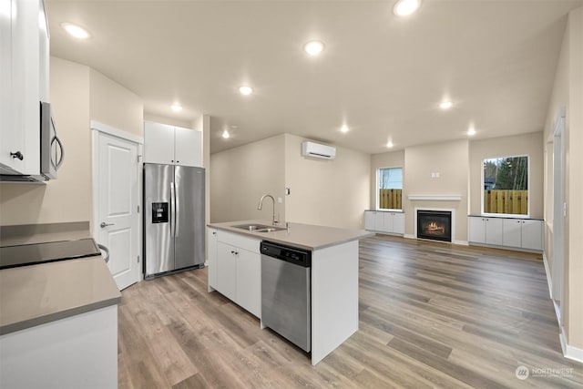 kitchen featuring white cabinets, sink, an island with sink, and stainless steel appliances