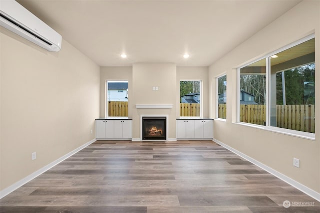 unfurnished living room with hardwood / wood-style floors and an AC wall unit