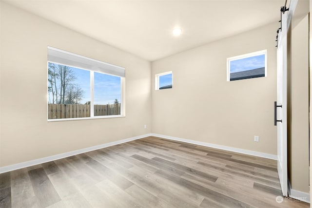 empty room featuring a barn door and light hardwood / wood-style flooring