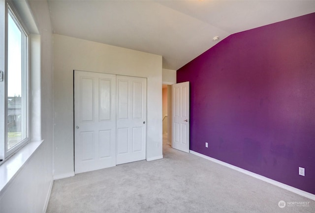 unfurnished bedroom with a closet, vaulted ceiling, and light carpet