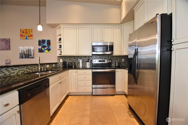 kitchen featuring light tile patterned floors, appliances with stainless steel finishes, decorative backsplash, pendant lighting, and sink