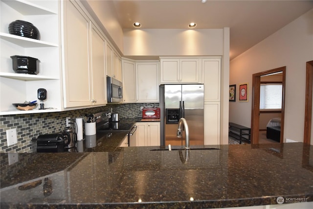 kitchen featuring white cabinets, stainless steel appliances, tasteful backsplash, dark stone countertops, and sink