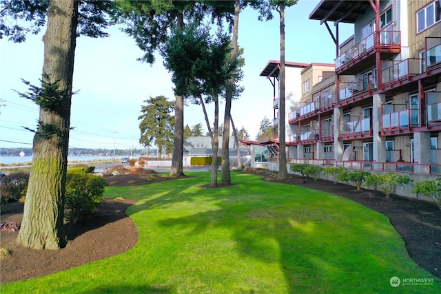 view of property's community with a lawn and a water view